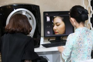 Chuyên viên đang soi da khi thực hiện quy trình chăm sóc da mặt tại spa cho khách hàng