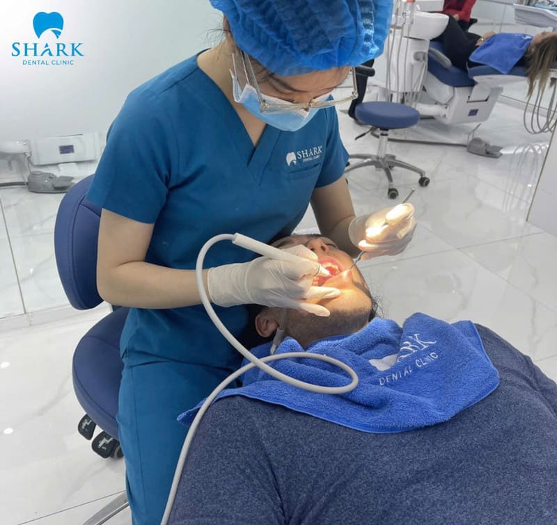 Dentists at Shark Dental Clinic are performing oral cleaning for a customer before placing porcelain dental bridges