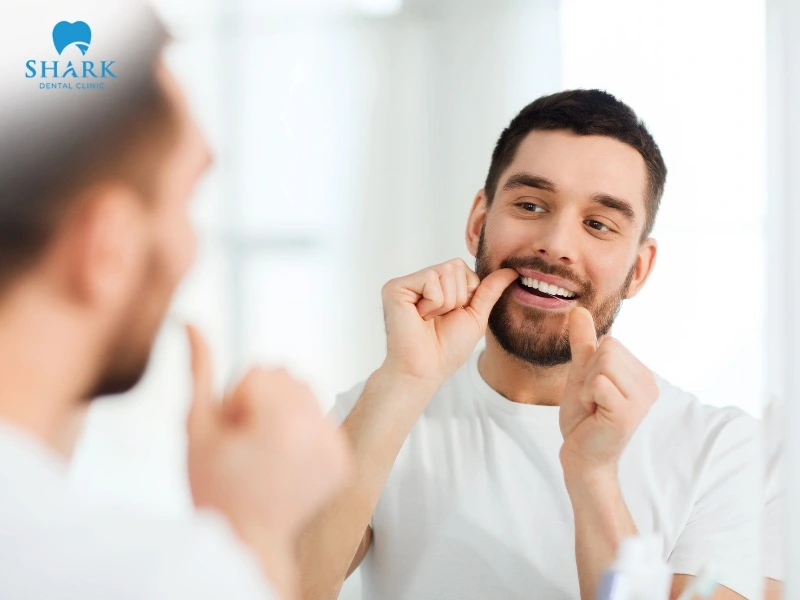 To floss, wrap the string around both index fingers and gently move it up and down along the sides of the teeth to remove plaque and bacteria