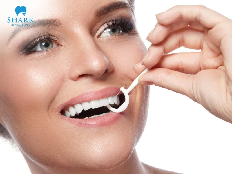Hold the handle of an interdental pick and gently insert the tip between the teeth to remove leftover food and plaque