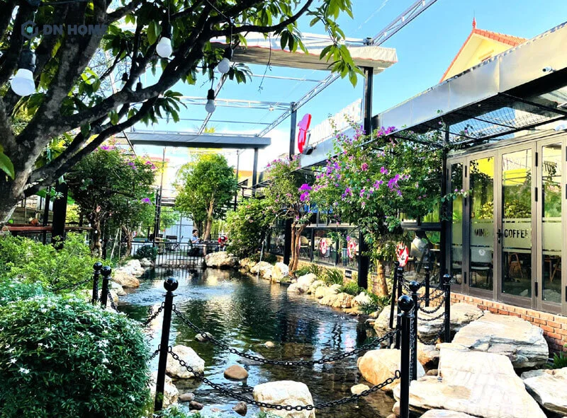 Quán cà phê ngoài trời với hồ cá koi, cây xanh và đèn treo nghệ thuật