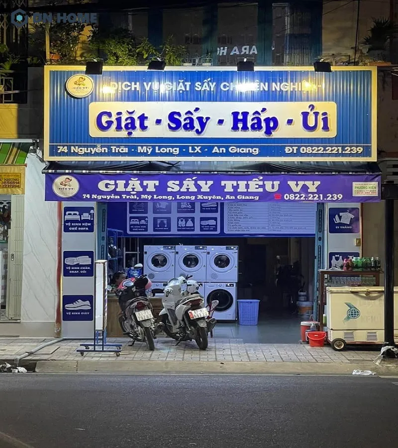 Mẫu bảng hiệu giặt sấy có lắp thêm đèn chiếu sáng, làm nổi bật cửa tiệm hơn vào ban đêm