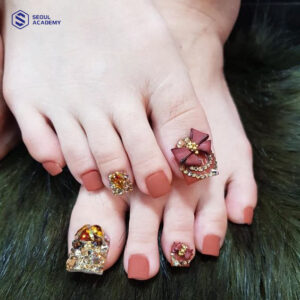 Sơn móng chân màu cam đất đính charm và đá lấp lánh