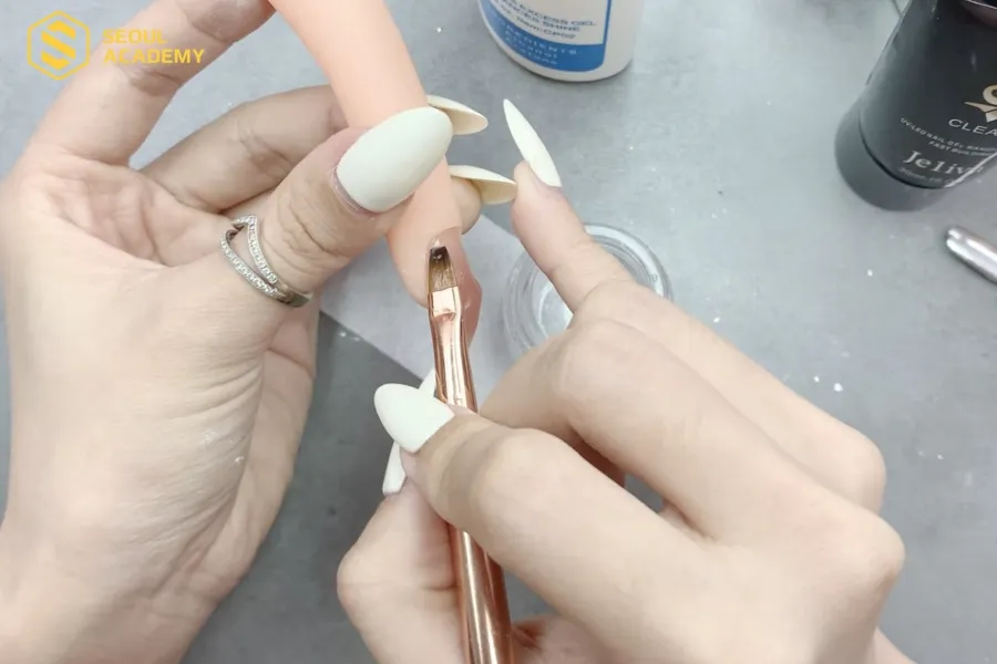Từ từ dùng cọ đẩy gel phủ toàn bộ bề mặt móng