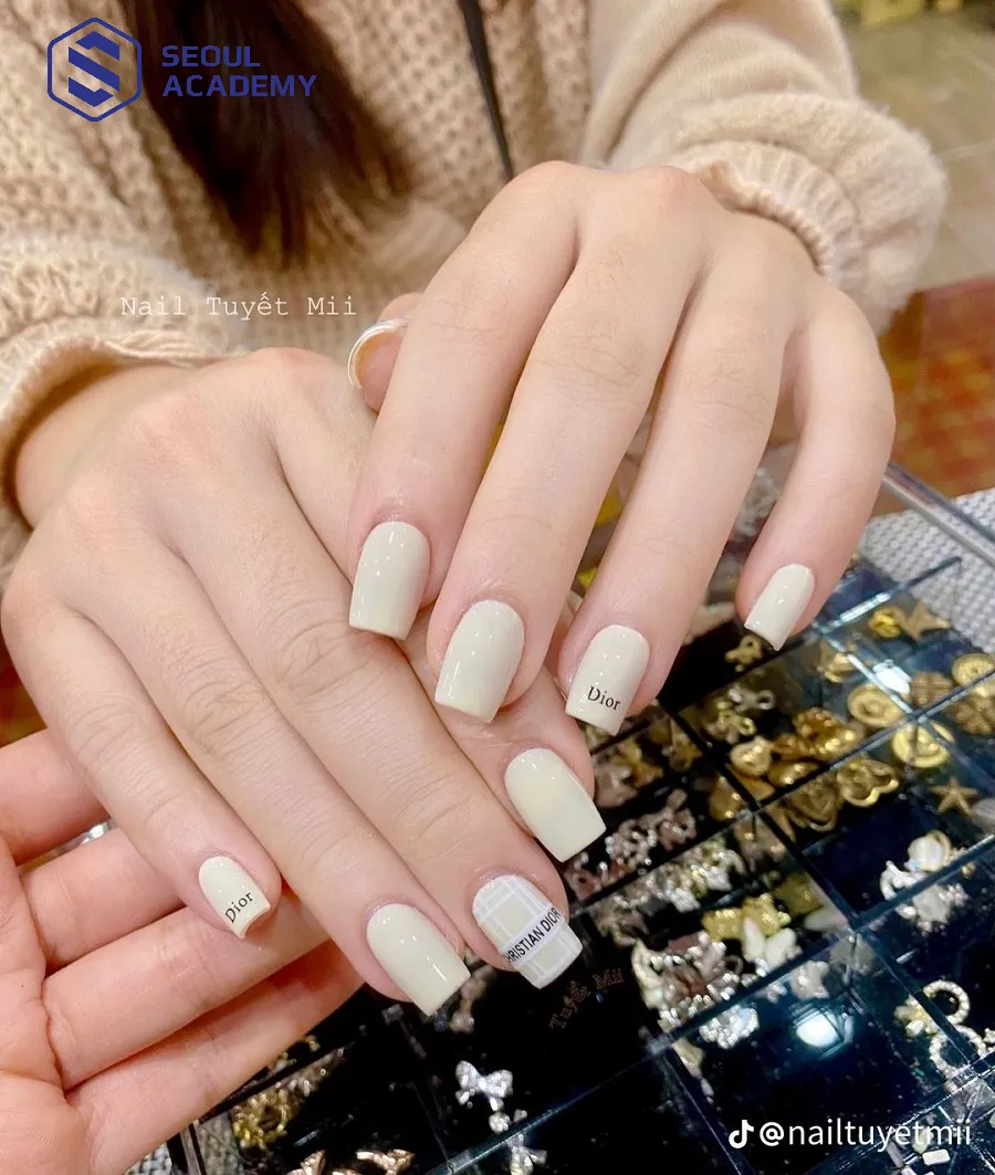 Mẫu nail trắng sữa vẽ chữ kết hợp đính phụ kiện sang trọng Mẫu nail trắng sữa vẽ chữ kết hợp đính phụ kiện sang trọng