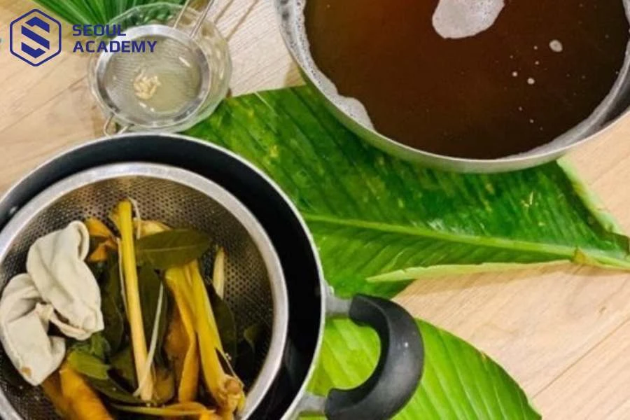 Dùng vợt để lọc bã thảo mộc sau quá trình chưng cất