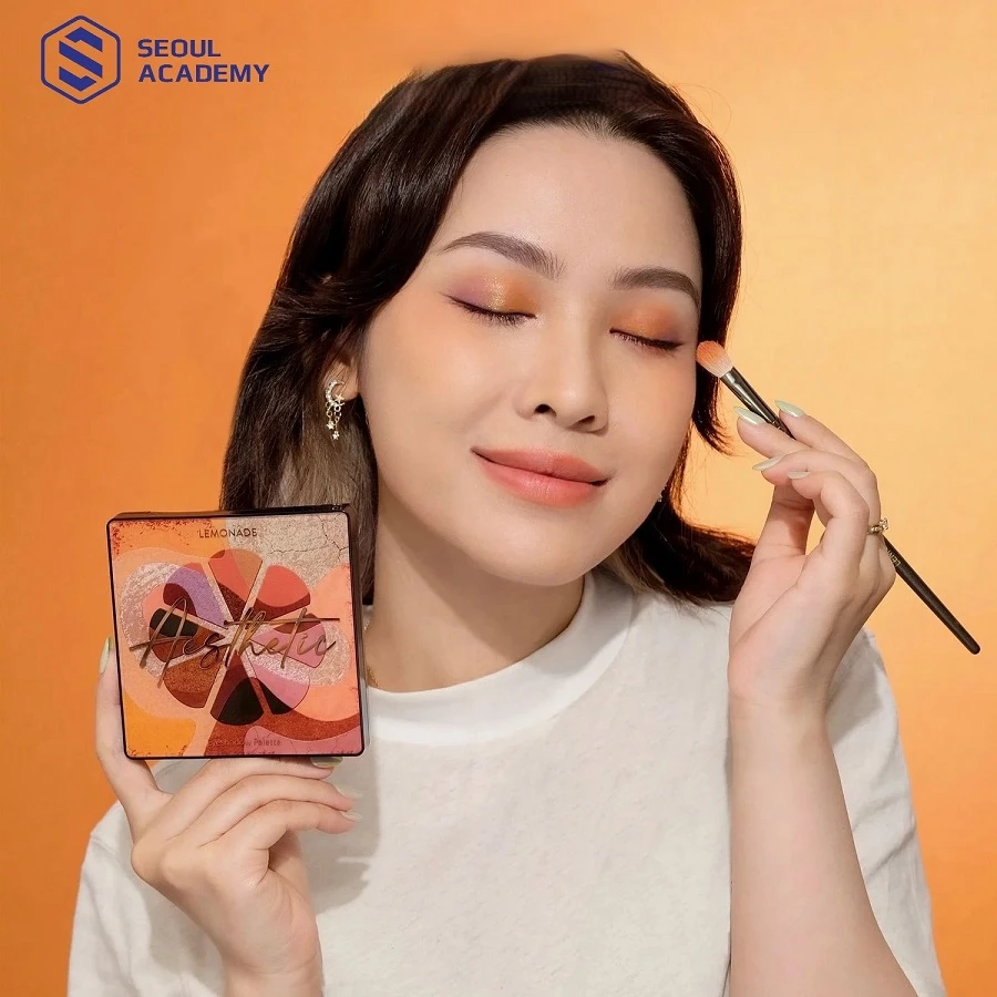 Đây là bước quan trọng nhất trong trang điểm mắt tone cam. Bạn hãy chọn tone màu cam làm chủ đạo (cam đào, cam đất, cam san hô) tán lên ⅔ bầu mắt, tập trung nhiều hơn ở phần đuôi mắt và một chút ở viền mi dưới. Sau đó sẽ dùng một tone cam đậm hơn hoặc màu nâu cam nhấn vào góc chữ V ở phần đuôi mắt, tạo hiệu ứng đôi mắt to tròn, có chiều sâu hơn. Cuối cùng lấy ngón tay lấy một ít phấn nhũ vàng hoặc nhũ cam dặm nhẹ vào chính giữa bầu mắt và khóe mắt để tạo hiệu ứng lung linh, bắt sáng.