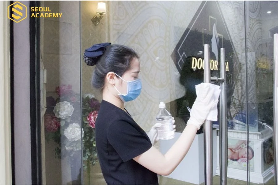 Nhân viên spa vệ sinh tay nắm cửa, nơi mà khách hàng tiếp xúc nhiều nhất