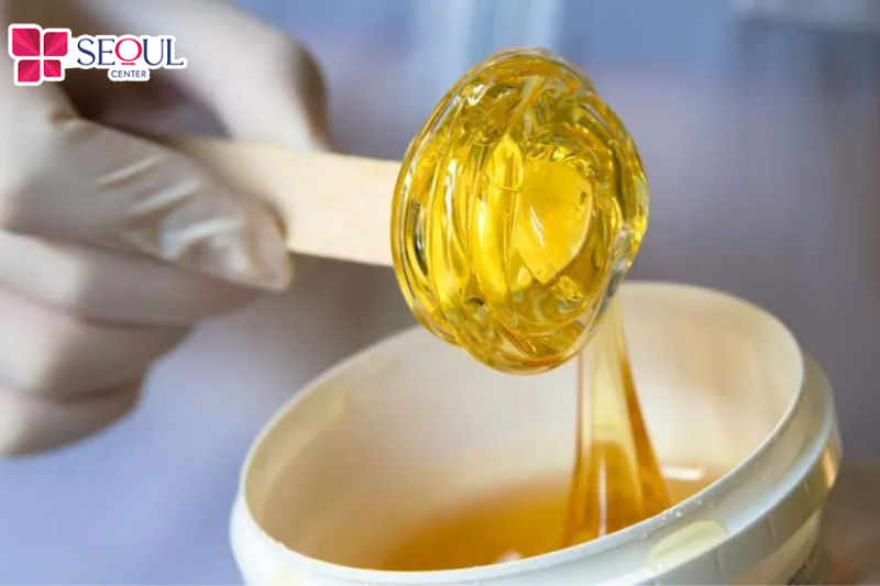 Dùng que gỗ để lấy lượng sugaring cần thiết bôi đều lên vùng cần wax