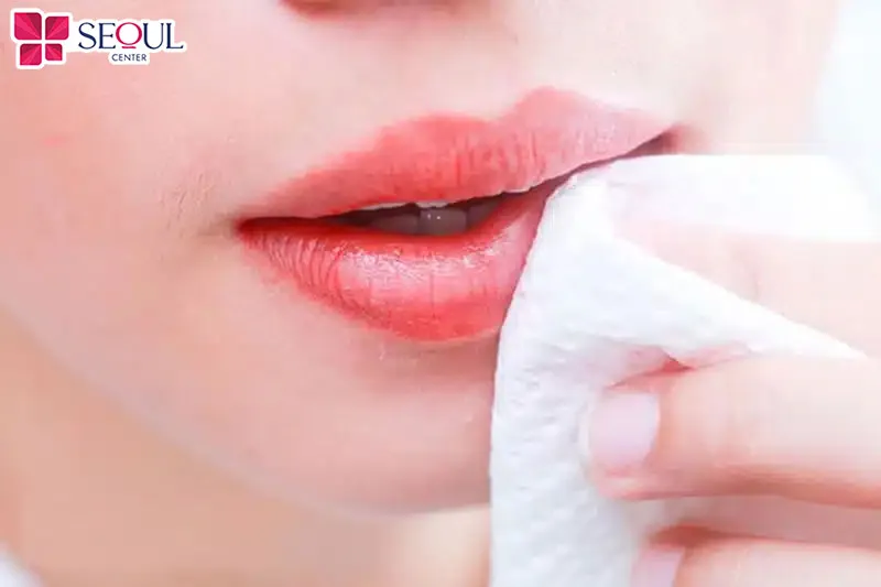 Làm sạch môi bằng bông gòn và nước muối sinh lý