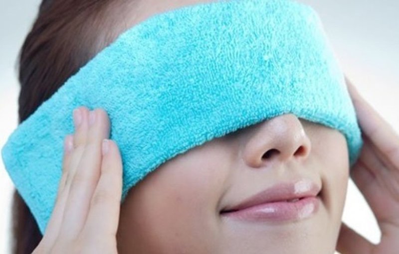 Chườm khăn ấm lên mắt để mắt đỡ mệt mỏi