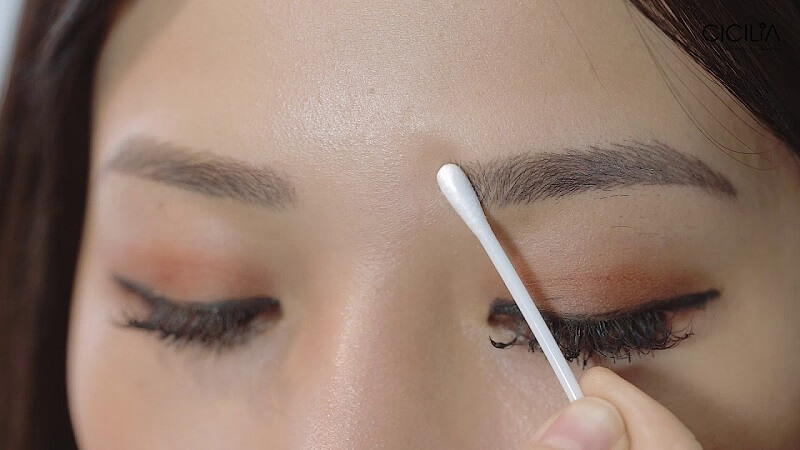 Dùng bông tăm thấm nước ấm hoặc nước muối sinh lý để vệ sinh chân mày